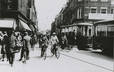 863575 Gezicht in de Lange Viestraat te Utrecht vanaf het Vredenburg, met druk fietsverkeer, een verkeersagent en twee trams.